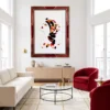 Salon moderne avec canapé gris, table basse en bois et grand tableau, Horizon Suspendu de l'Artiste Alessandra Viotti-Gilabert, encadré de rouge représentant une femme stylisée